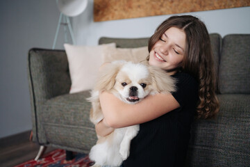 Young dog owner girl plays with her dog at home indoors