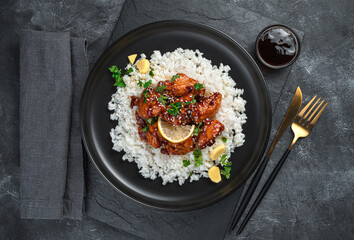 Chicken with sweet and sour teriyaki sauce and rice on a dark background.