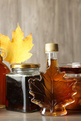 Bottle and jars of tasty maple syrup on wooden table