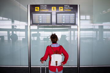Unrecognizable traveler sitting near timetable in airport