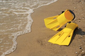 Pair of yellow flippers on sand near sea. Space for text © New Africa