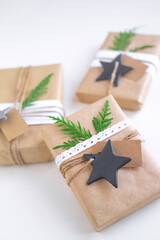 Vintage gift boxes on white background. Eco style gift wrapping: natural rough paper, jute rope, gift signing labels, branches of a christmas tree for decor. Top view. Vertical orientation