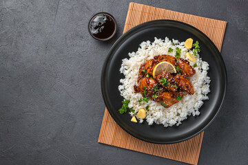 Chicken in sweet and sour sauce and rice on a black background.