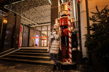 beautiful young woman in the winter near the store with the inscription sale and Christmas decorations. Christmas discounts and sales