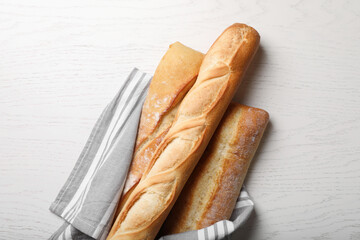 Different tasty baguettes on white wooden table, flat lay