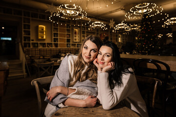 two beautiful women in a cozy cafe with beautiful glowing chandeliers