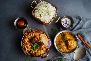 Indian veg non veg meal thali - mutton biryani, raita, malai kofta, basmati rice,  and gulab jamun, selective focus