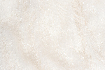 Texture of soft white plaid surface with long natural fur at bright light view from above. Blanket or clothes material closeup