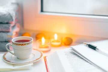 autumn still life. books, leaves, cup and candlestick on window. Concept of autumn reading time and romantic