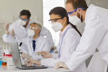 Scientists working together to analyze samples while working in a modern research laboratory. Men...