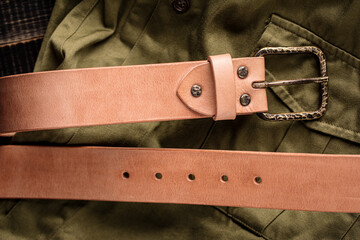 Handcrafted light brown leather strap belt on fabric background