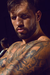 portrait of a sexy european boxer in a tattoo. an athlete with a strong, healthy, muscular body, in a dark gym.