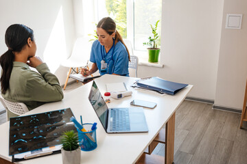 White woman doctor talking with patient while working in her office