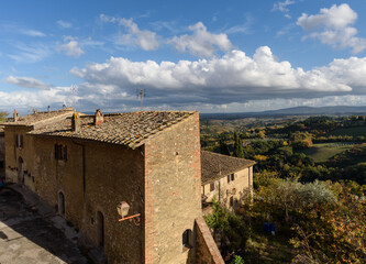 Fototapeta premium Blick über toskanische Landschaft im Herbst bei Sonnenschein und Wolken und Haus im Vordergrund