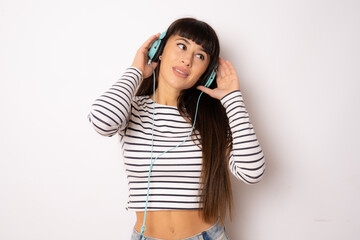 Beautiful young woman with long hair wearing headphones listening music isolated over white background.