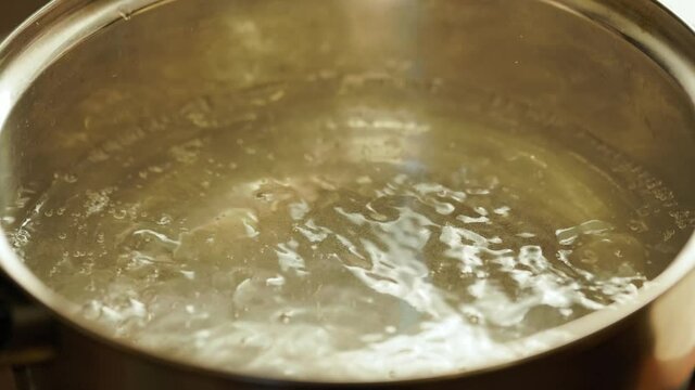 clean water boiling in stainless steel pot - slo-mo close-up
