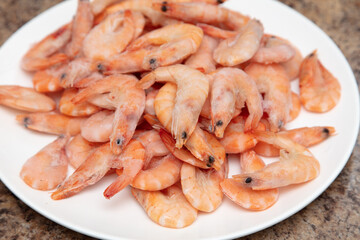 Red frozen shrimps on a white plate.