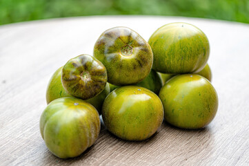 fresh and delicious tomatoes of green-black colored sort on a wooden table, closeup