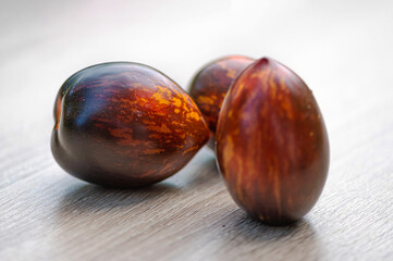 fresh picked multicolored striped and streaky black, purple, and red tomatoes on a wooden table