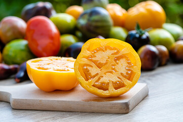 table with a cutting board with sliced tomatoes and different colored tomatoes in the background