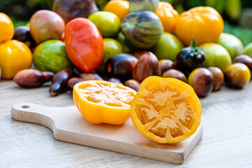 table with a cutting board with sliced tomatoes and different colored tomatoes in the background