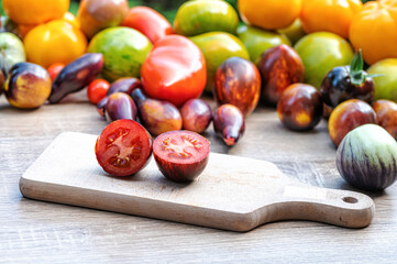 table with a cutting board with sliced tomatoes and different colored tomatoes in the background