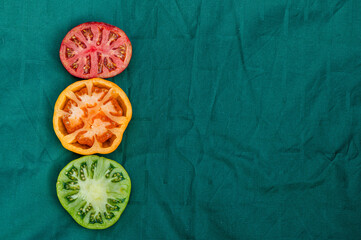 red, yellow and green tomato halves on a green background, closeup from above, abstract semaphore
