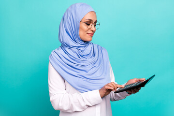 Photo of sweet cute young woman wear arab headscarf spectacles counting taxes isolated turquoise...