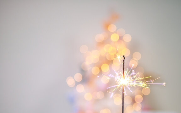 Beautiful sparkles from sparklers on the background of New Year's bokeh, Christmas mood, glitter, festive background.