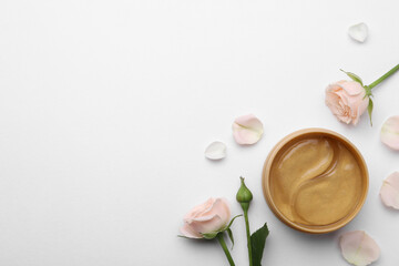 Under eye patches in jar and rose flowers on white background, flat lay. Space for text