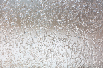 Frozen drops of water on a glass window as an abstract background.