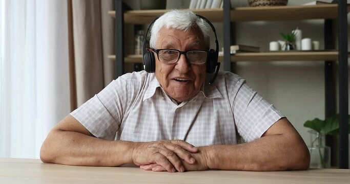 Screen view portrait of old age man in headphones professional coach expert look at web camera talk to audience present webinar online. Confident mature speaker lead virtual training in conference app