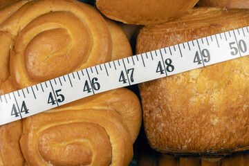 The problem of excess weight. Weight problem. Measuring tape in inches over sweet pastry.  