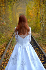 Pani młoda w sukni ślubnej z trenem na torach w tunelu z drzew. Tunel miłości w Klewaniu na Ukrainie. - obrazy, fototapety, plakaty