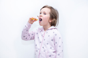 The child thoroughly brushes his teeth with a toothbrush and toothpaste. Hygiene of teeth and oral cavity. Caucasian girl on a gray background.