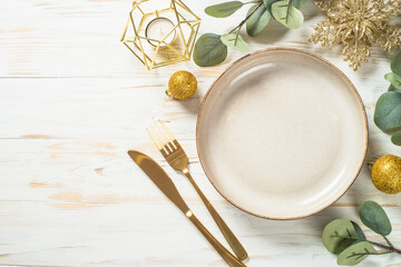 Christmas table setting with eucalyptus leaves and luxury metallic golden decorations. Top view at...