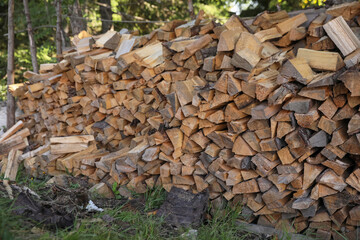 Stack of cut firewood on green grass outdoors. Heating in winter