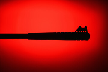 Silhouette of weapons on a red and black background. Part of a rifle. Armed Forces Concept