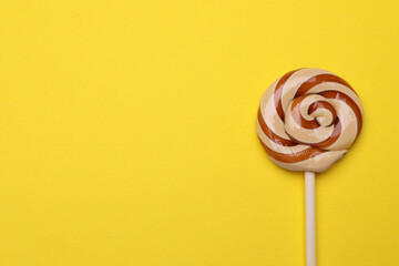 Delicious lollipop on yellow background, top view. Space for text