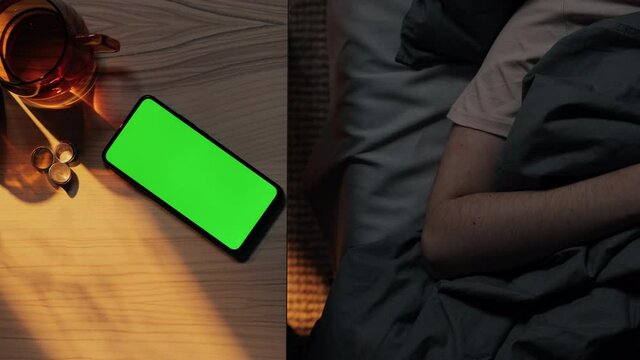 Woman put mobile with green screen on table before sleeping