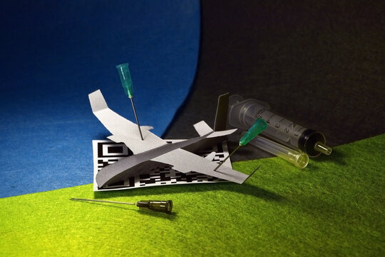 Airplane model pinned with a syringe needle to the vaccination QR code