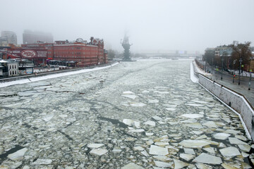 View on the red brick building of the historic chocolate factory and the bronze monument to Peter the great on the Moscow river on a foggy winter morning. Misty winter morning in Moscow