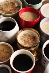 Many cups of different coffees on wooden table
