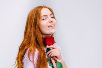 Attractive girl with a red rose. Charming appearance. Natural beauty with freckles.