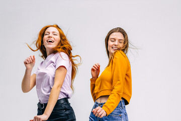 Two female girlfriends 20s in pastel pink orange sweaters dancing fooling around having fun...