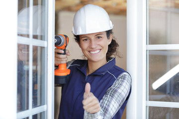 woman builder holding a driller and thumbs ups