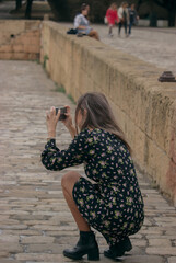 Blonde girl taking photo with cellphone of tourists outdoors. Travel during corona virus 2021.