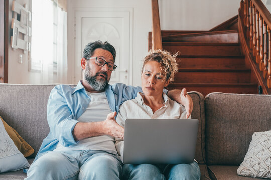Shocked caucasian couple looking at laptop screen frustrated by unexpected bad news online. Husband and wife disappointed and feeling anxious on losing money in online lottery,