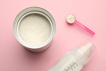 Feeding bottle with infant formula and powder on pink background, flat lay