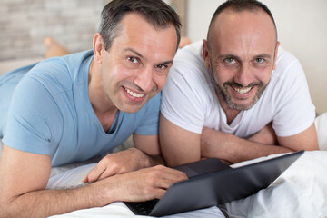 gay couple relaxing together  with a laptop computer